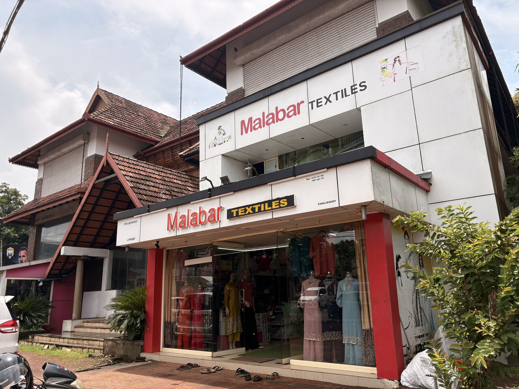 Street-facing frontage of nālukettu with shop units and Kerala roof detail